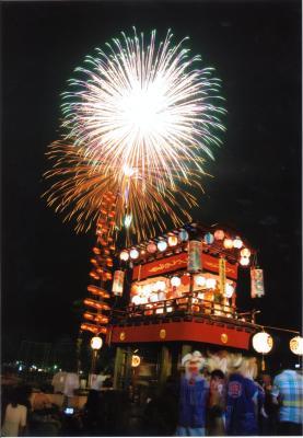 山車の上に打ち上げ花火が上がった祇園まつりの様子の写真