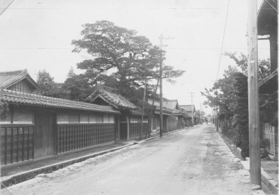 道路沿いに瓦のひさしがついた塀がたてられている伊勢街道のモノクロ写真