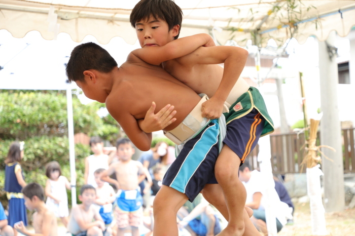 短パンの上から回しを付けた2名の男の子が相撲をとっている写真