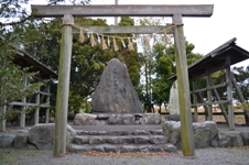 鳥居の奥に三角形の大きな石碑が設置されたカケチカラ発祥の地の写真