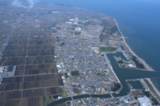 右側に海があり左側に向かって住宅地から田畑にかけて大きな川が流れている大淀の地域を上空から撮影した写真