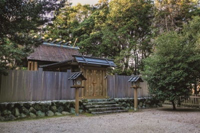周囲を樹木に囲まれ、積み上げた石の土台の上に木材で囲われ中が見えにくい造りになっている竹神社の写真