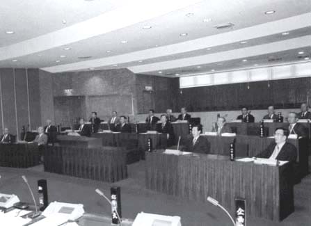議員が2名ずつ長机の席につき話し合いが行われている議場の写真