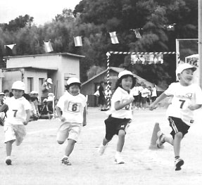 運動会でかけっこをしている4人の子供たちの写真