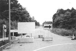 道路の前にガードレールや右向き矢印の看板がたてられている多気停車場斎明線の写真