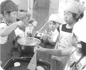 ボウルの中の生地をホットプレートで焼いている子供たちの写真