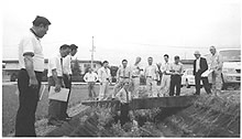 用水路の周りに集まって調査をしている数名の職員の写真