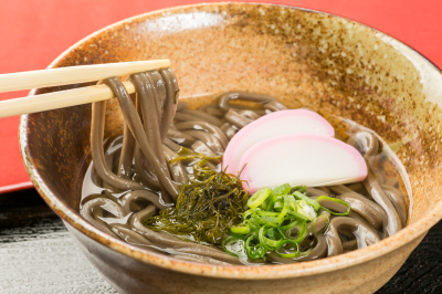 ひじきの粉末を練りこんだ麺に蒲鉾やネギなどが入ったひじきうどんの写真