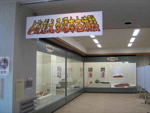L字型のショーケースに遺跡が展示されている「よみがえる坂本古墳群」企画展の会場内の写真