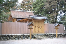 周囲を樹木に囲まれ、積み上げた石の土台の上に木材で囲われ中が見えにくい造りになっている竹神社の写真