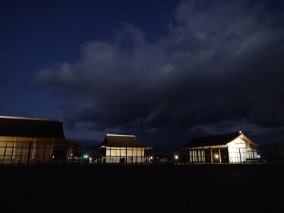 上空に雲が現れ復元建物3棟がライトアップされているさいくう平安の杜の写真