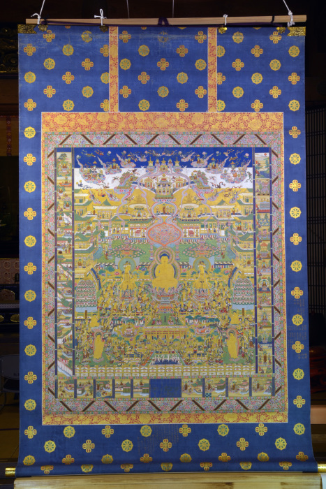 中央に大きな仏様、全面に多くの仏が描かれた観無量寿経曼荼羅の掛け軸の写真