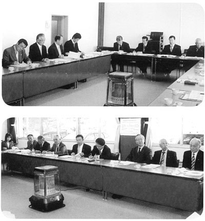 上：コの字型に設置された長机の中央にストーブが置かれ、席についている委員が話し合いをしている写真、下：資料が置かれた席について話し合いをしている委員の写真