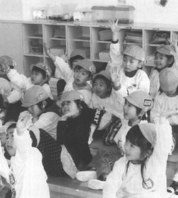 座って元気よく手を挙げているみどり保育所の園児たちの写真