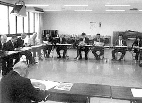 コの字型に設置されたテーブルに置かれた資料を見ながら話し合いをしている委員の写真