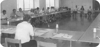 ロの字型に設置された席につき、手元の資料を見ながら話し合いをしている教育厚生常任委員の写真