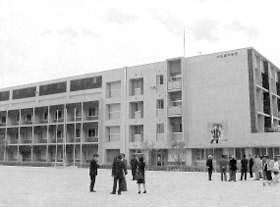 4階建ての大山崎中学校校舎を校庭から眺めている視察委員の写真