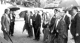 傘をさして多賀城跡の説明を聞いている視察委員の写真