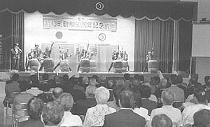 舞台上で行われている和太鼓の演奏を鑑賞している式典参加者の写真