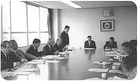 会議用のテーブルに向かい合うように議員が着席し、話し合いをしている北海道南幌町の議会の様子の写真
