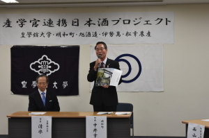 産学官連携日本酒プロジェクトの会場で、中井町長が資料を左手に持ち、マイクを持って話をしている写真